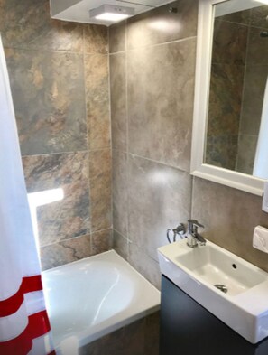 Un baño moderno con una bañera, un lavabo y un espejo.