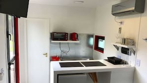 Una cocina compacta con microondas, tostadora y lavamanos pequeño.