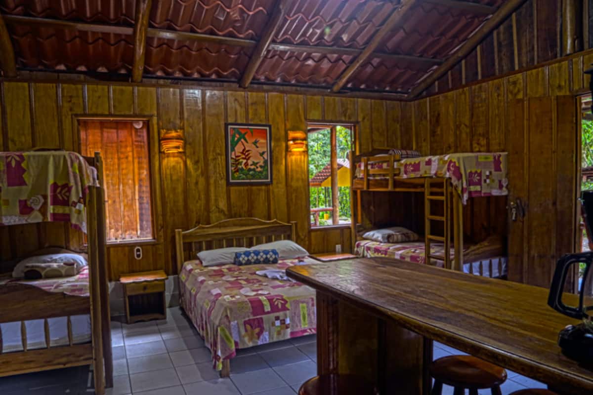 A rustic wooden cabin with bunk beds, a wooden table, and a bench.