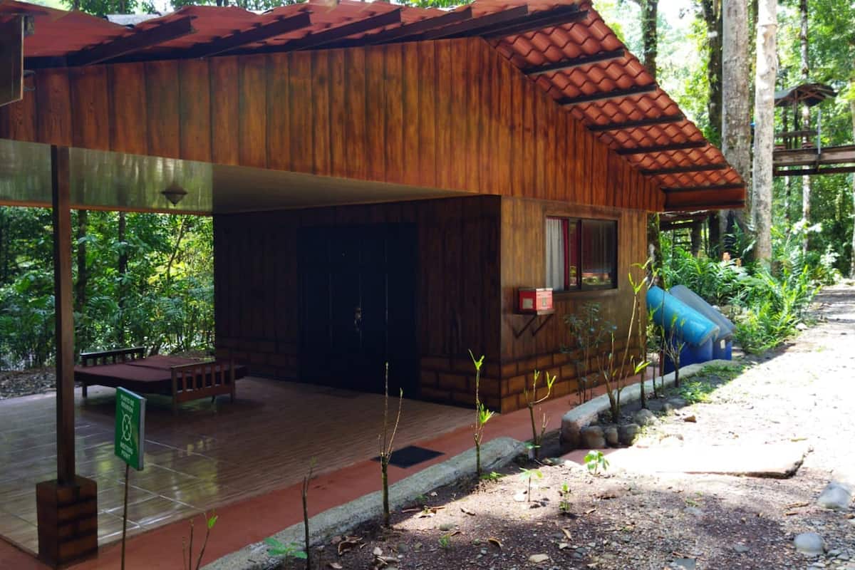 A wooden cabin with a tiled roof, a covered porch, and a small window.