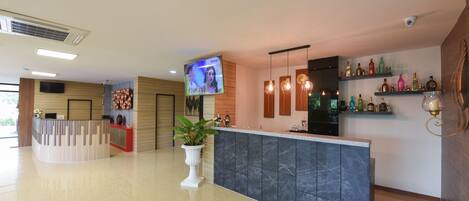 A modern reception area with a marble counter, a flat-screen TV, and a plant.
