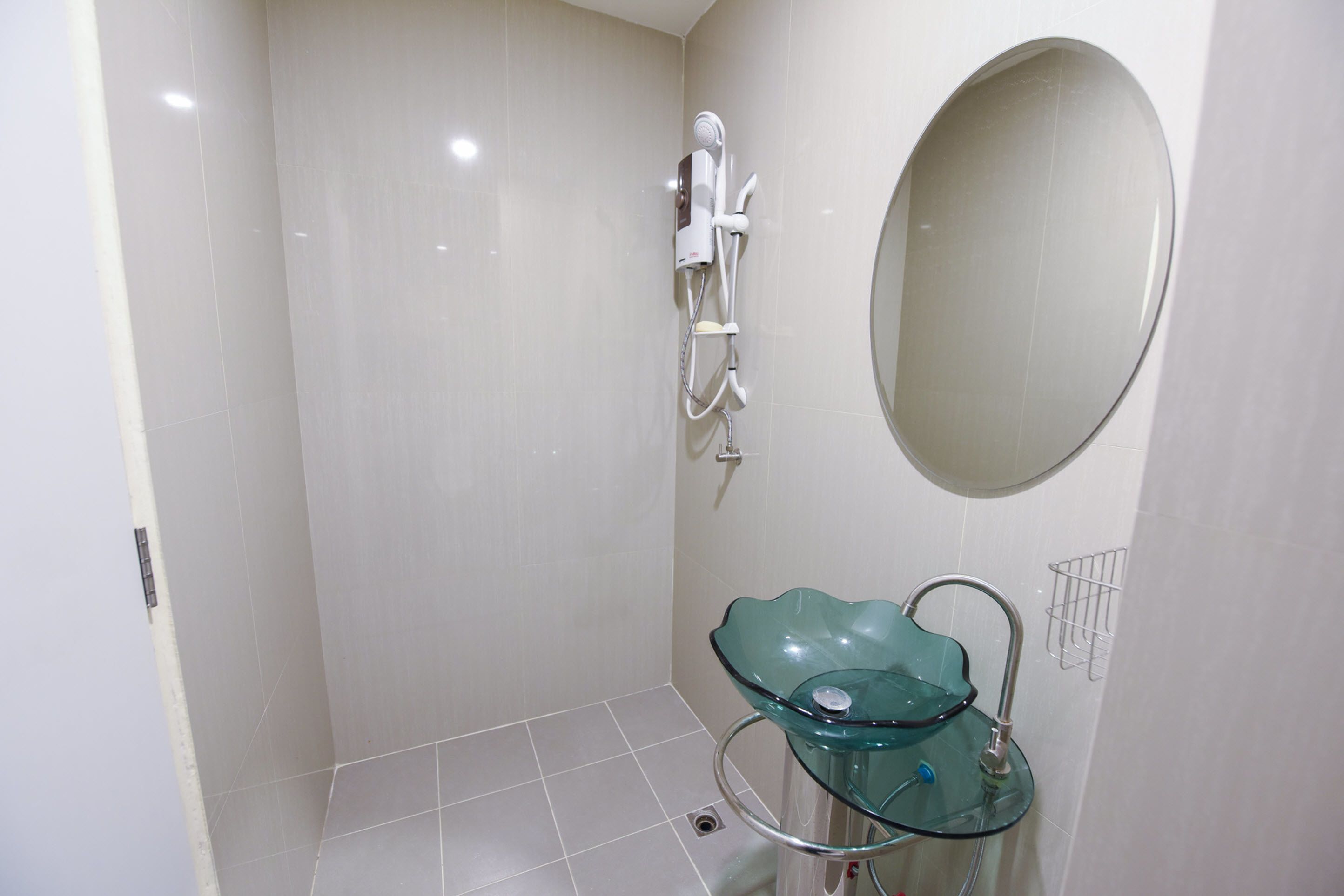 A bathroom with a glass sink, a handheld showerhead, and a wall-mounted mirror.