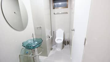 Un baño pequeño con un lavabo de vidrio, un inodoro y un espejo.