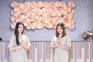Two individuals standing in front of a wall with a circular pattern. - Wish Hotel Ubon (Ubon Ratchathani)