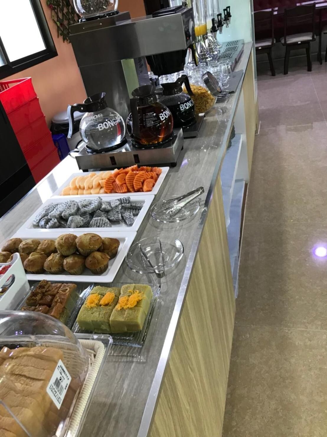 A buffet counter with various food items including pastries, muffins, and desserts.