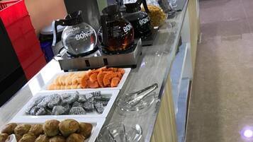 A buffet counter with various food items including pastries, muffins, and desserts.