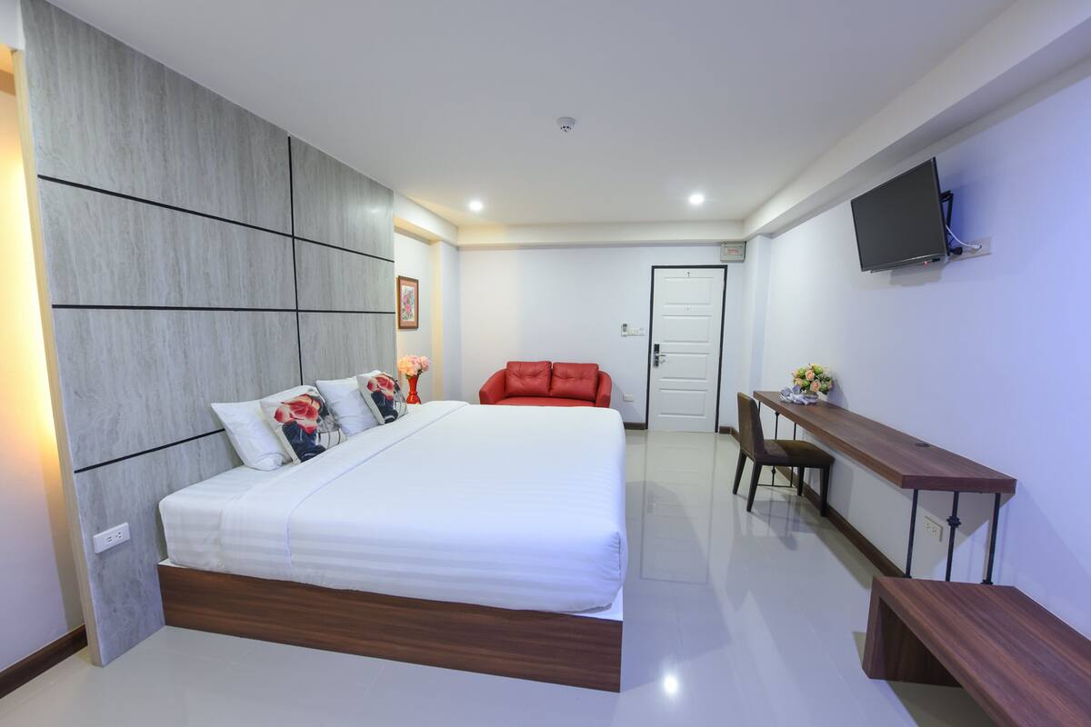 A modern bedroom with a large bed, a desk, and a television.