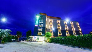 A multi-story hotel with illuminated signage, a well-maintained outdoor area, and a clear view of the building's facade. - Wish Hotel Ubon (Ubon Ratchathani)