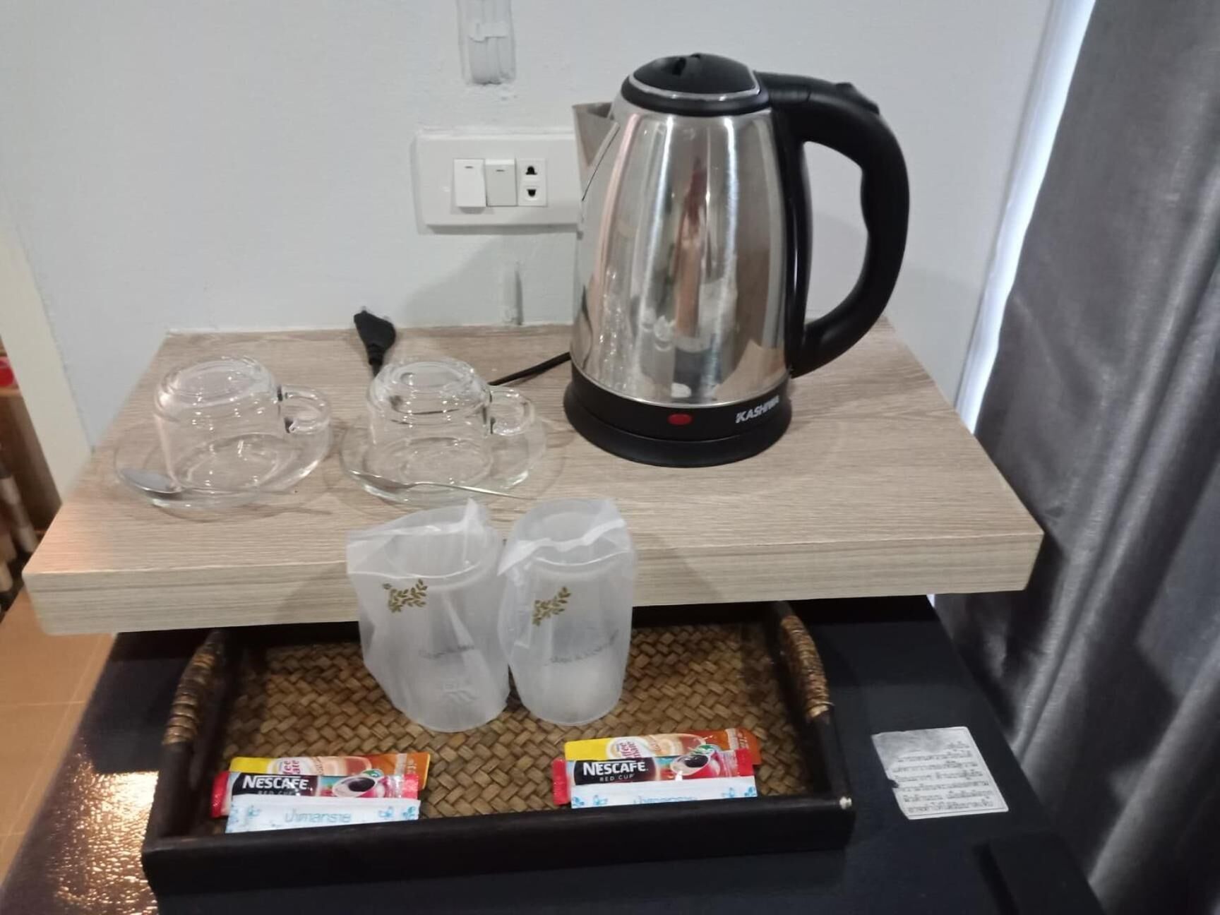 A breakfast setup with a coffee maker, glasses, and Nescafe packets on a tray.