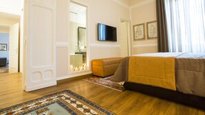 A hotel room with a bed, a television, a mirror, and a door leading to another room.