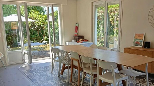 Un espace repas comprenant une grande table, des chaises et un sol à motifs.