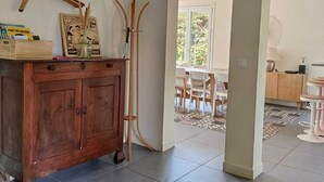 Une pièce spacieuse avec un meuble en bois, un coin repas comprenant des chaises et une table, et une vue sur l’extérieur.