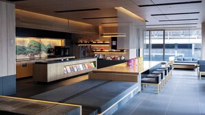 A modern cafe with a wooden counter, seating area, and large windows. - Tokyu Stay Kyoto Sakaiza Shijo-Kawaramachi (Kyoto)