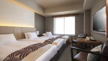 Habitación de hotel con dos camas, un escritorio y una televisión.