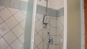Une douche équipée d’un pommeau de douche à main et d’un robinet fixé au mur.