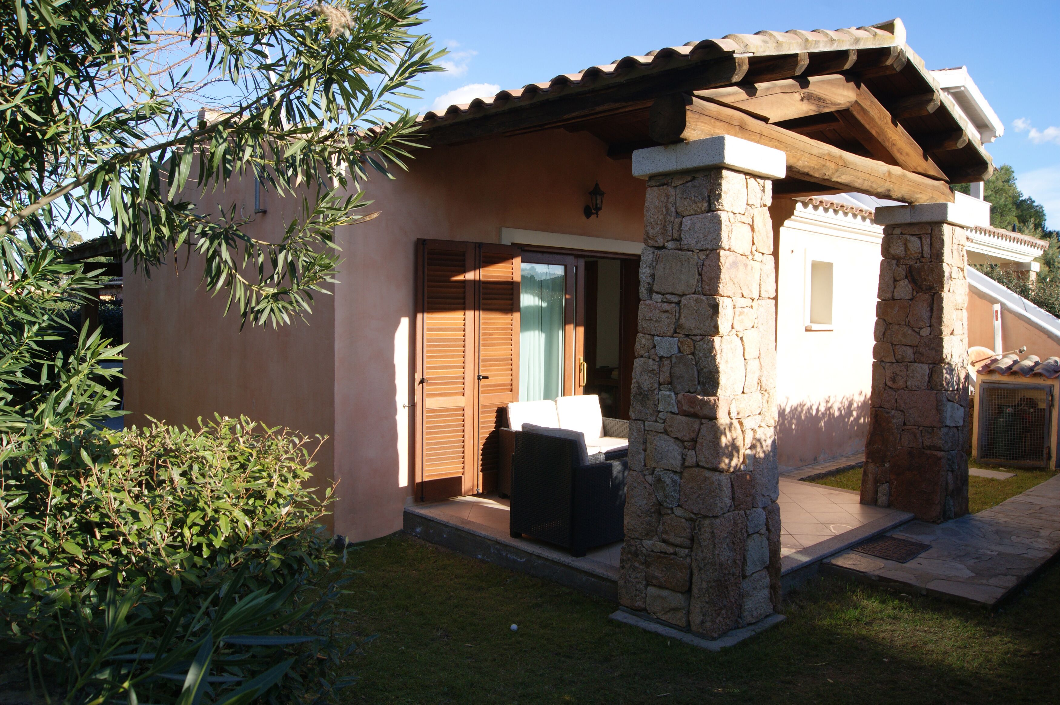 A house with a patio, stone pillars, and a door with shutters.