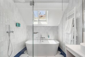 Ein modernes Badezimmer mit einer freistehenden Badewanne, einer gläsernen Dusche und einem Oberlicht.