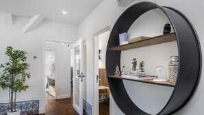 A hallway with a potted plant, a round black shelf with decorative items, and a door leading to another room. - New! Everything BRAND new 23-  Luxury Prime Location Great for Family & Friends (Lisboa)