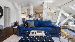 A modern living room with a blue sofa, a coffee table, and a dining area in the background. - New! Everything BRAND new 23-  Luxury Prime Location Great for Family & Friends (Lisboa)