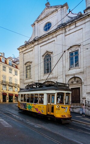Eine gelbe Straßenbahn fährt auf einer Straße in Lissabon, gesäumt von Gebäuden.