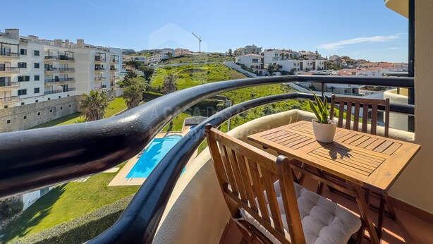 Un balcón con vista a una piscina, una silla y una mesa.