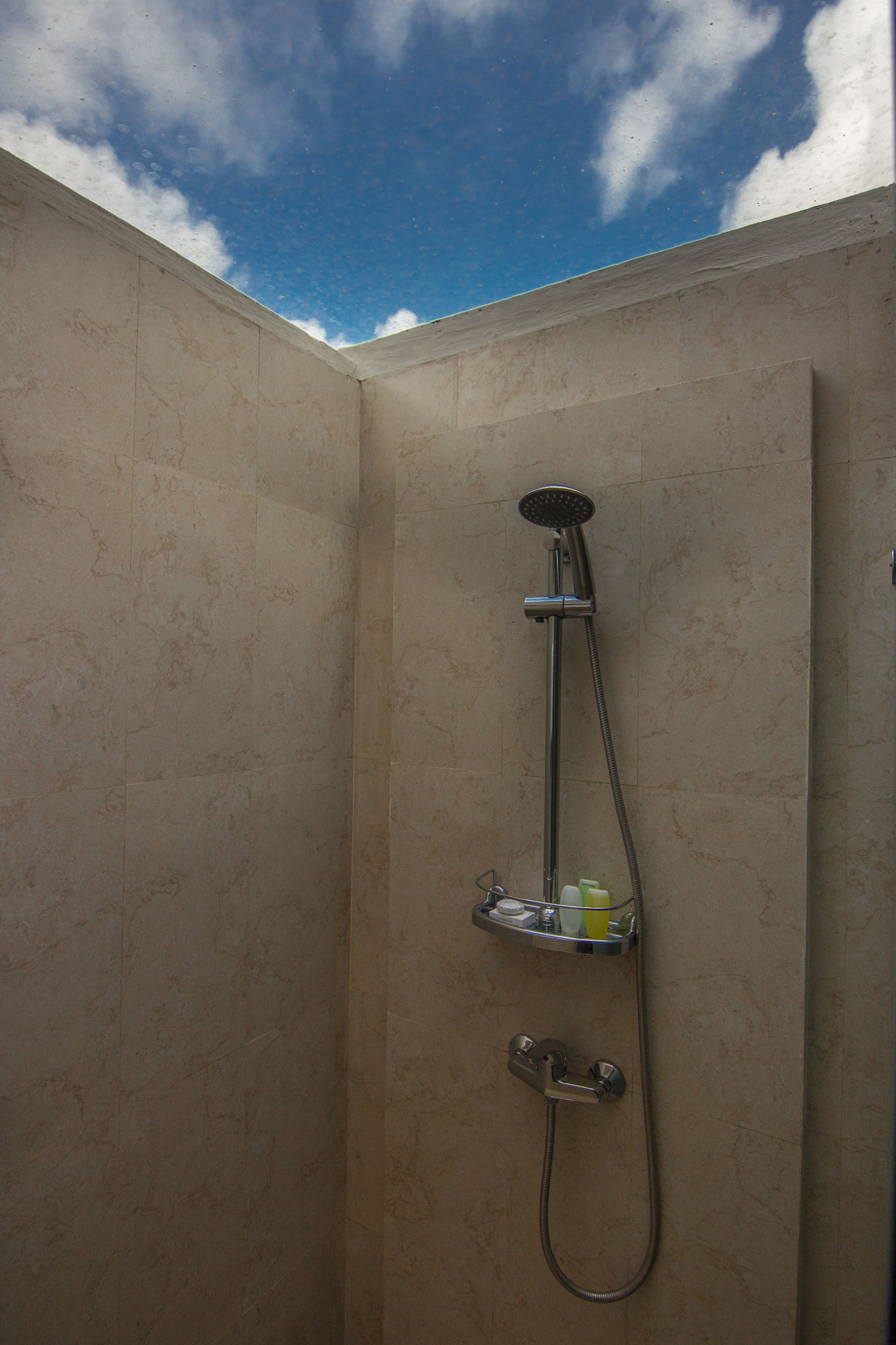Ein Badezimmer mit Dusche, Ablage für Toilettenartikel und Blick zum Himmel.