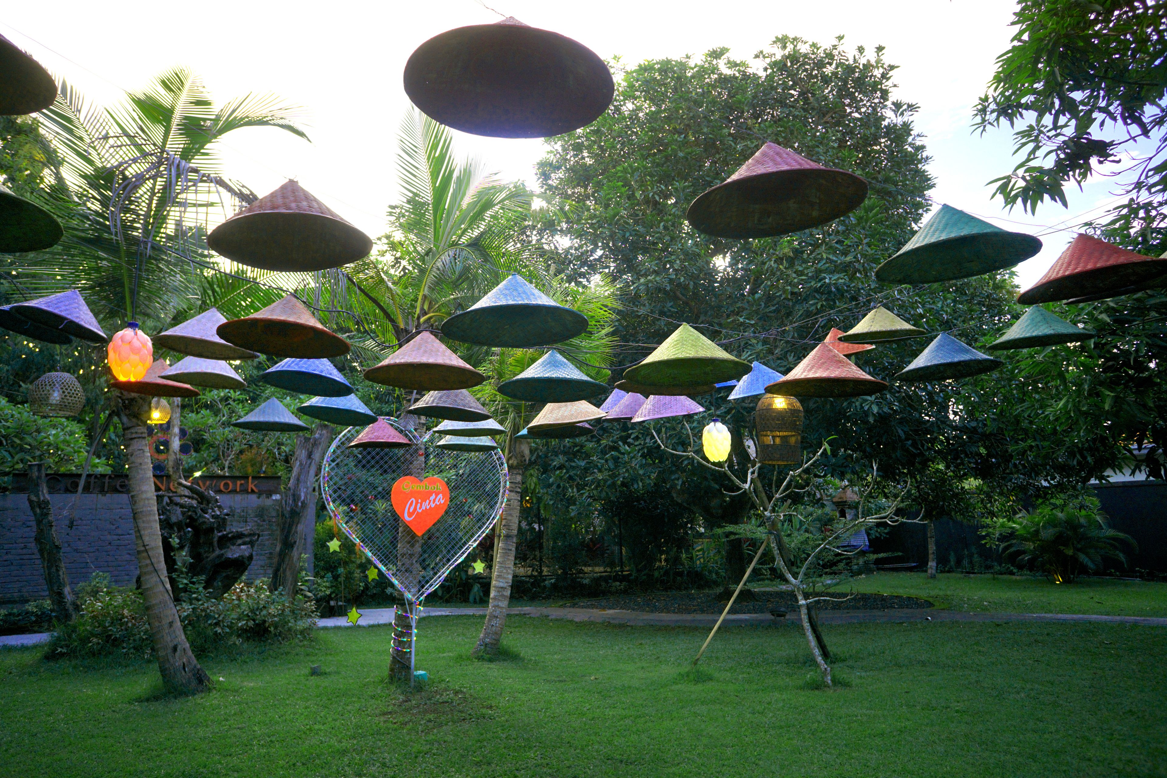 Un giardino con ombrelloni di varie forme e colori, un cartello a forma di cuore e un prato curato.