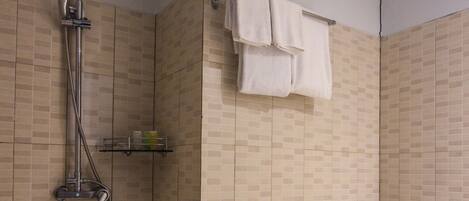 Un baño con ducha, inodoro y paredes de azulejos.