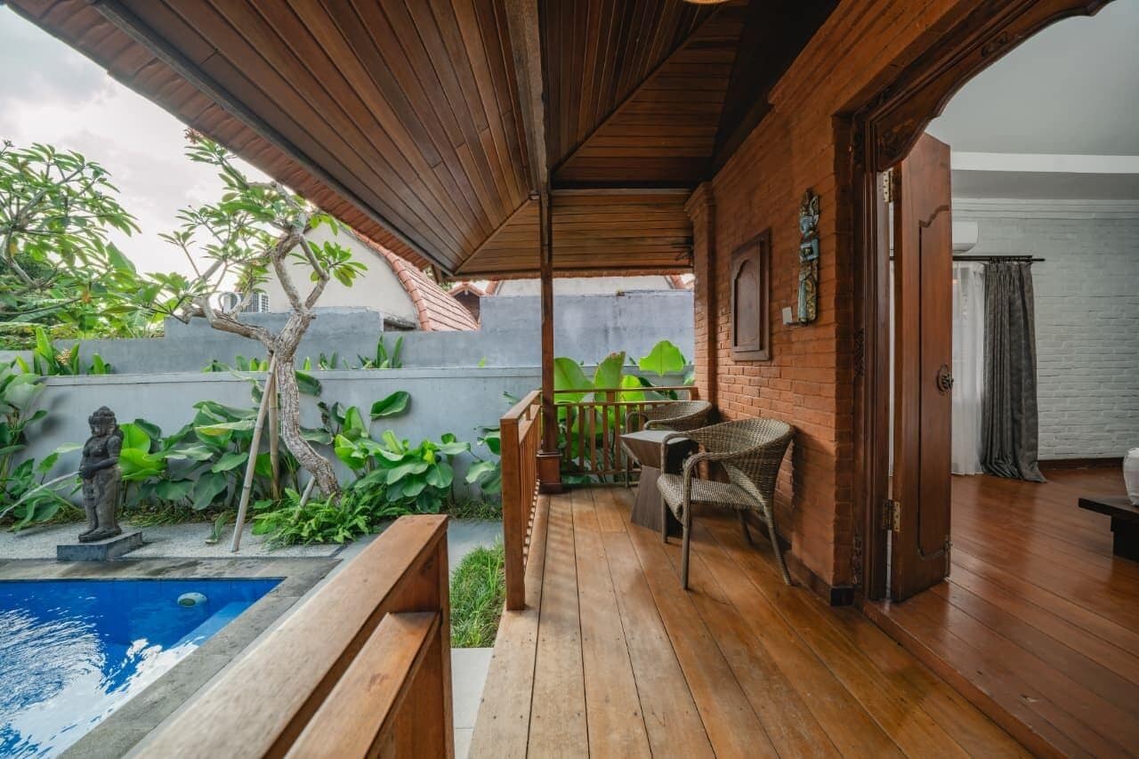 A wooden deck with a pool, outdoor furniture, and a statue.