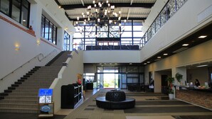 A spacious lobby with a central seating area, a staircase, and a reception desk.
