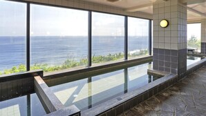 A modern indoor pool with large windows overlooking the sea.