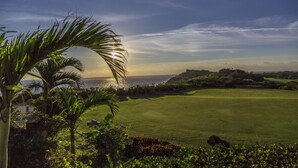 A golf course with a view of the ocean and a clear sky.