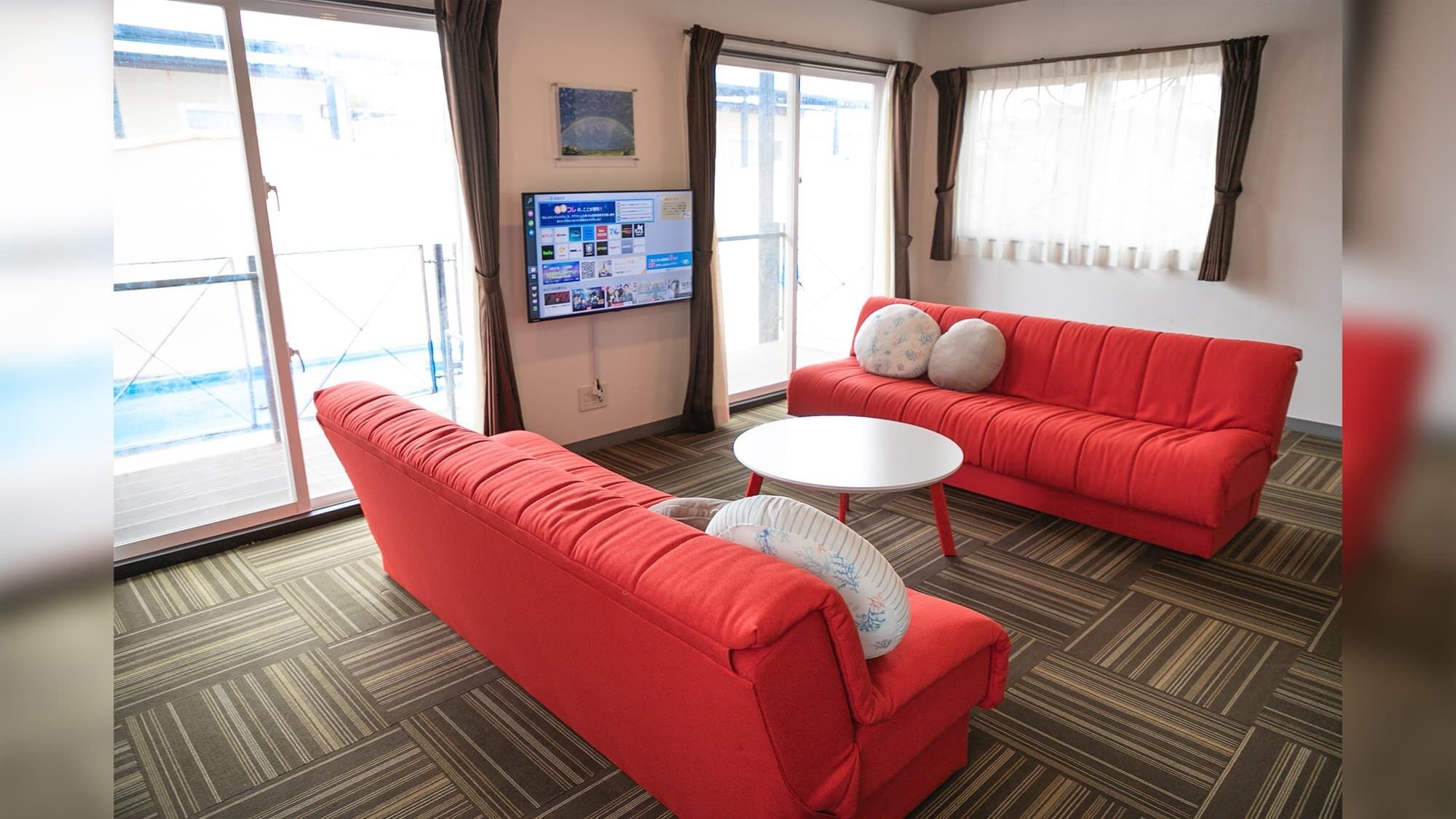 Ein Hotelzimmer mit einem roten Sofa, einem weißen runden Tisch und einem an der Wand befestigten Fernseher.