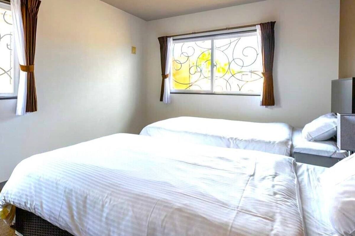Une chambre d’hôtel avec deux lits, une télévision et une fenêtre ornée de ferronnerie décorative.