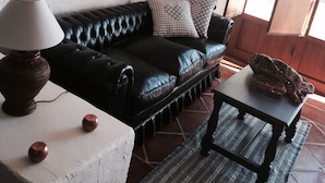 Ein Wohnzimmer mit einer schwarzen Ledersofa, einem kleinen Tisch und einer Lampe.