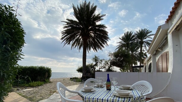 Un área de comedor al aire libre con una mesa dispuesta para dos, con vistas a una playa.