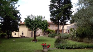 A courtyard with a peacock, a stone building, and a tree. - Three-room apartment, 80 square meters, 5/7 persons with swimming pool, 8 km from the center of Florence (Scandicci, Firenze)