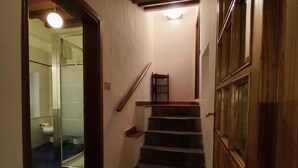 A narrow hallway with a wooden staircase leading to a door. A glass door on the left leads to a bathroom. - Three-room apartment, 80 square meters, 5/7 persons with swimming pool, 8 km from the center of Florence (Scandicci, Firenze)