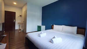 Une chambre d’hôtel avec un grand lit, un bureau en bois, une armoire et une porte.