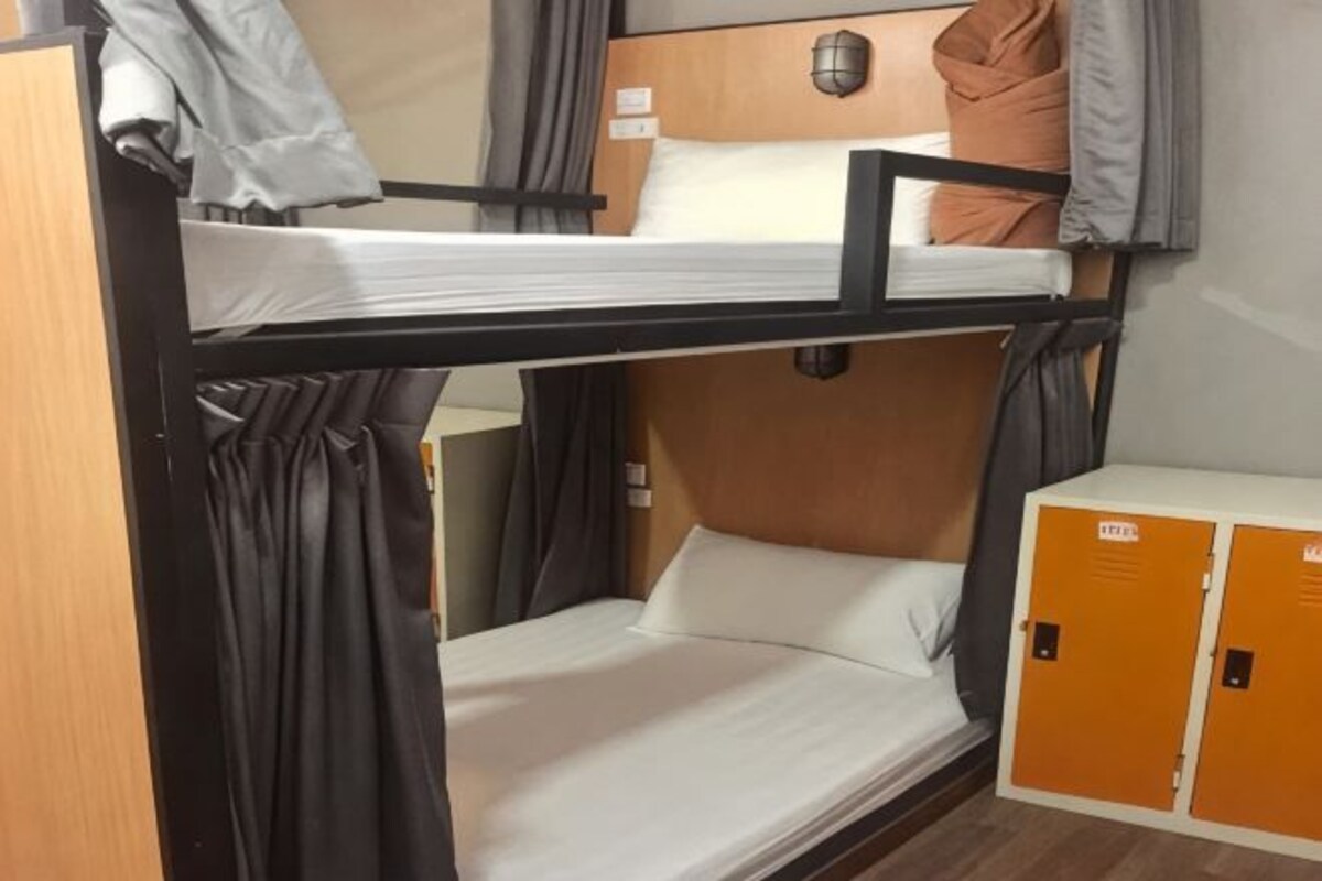A bunk bed room with a wooden headboard, a small table, and a wardrobe.