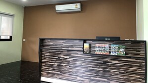 Un espace d’accueil au design moderne, avec un mur revêtu de panneaux en bois et un climatiseur fixé au mur.