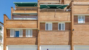 A multi-story brick building with white shutters, a green awning, and a visible phone number on the facade. - Golden Sunset Views - Panoramic Ocean View Duplex (Roses)