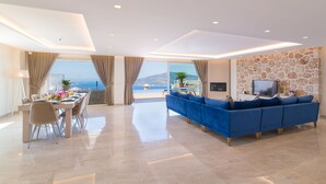 Una sala moderna con un sofá grande, un comedor con una mesa preparada para cuatro personas y una pared de acento de piedra.