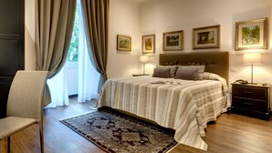 A bedroom with a bed, bedside tables, a chair, a window with curtains, and framed pictures on the wall. - Rome Boutique Apartments, central, delightful, close to the center and the vatican (6900333)