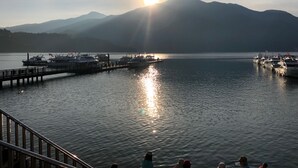 A calm lake with boats docked at a pier, surrounded by mountains and a clear sky. - Miracolo View Hotel (Yuchi)