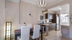 A modern kitchen with a central island, stainless steel appliances, and a dining area with white chairs.