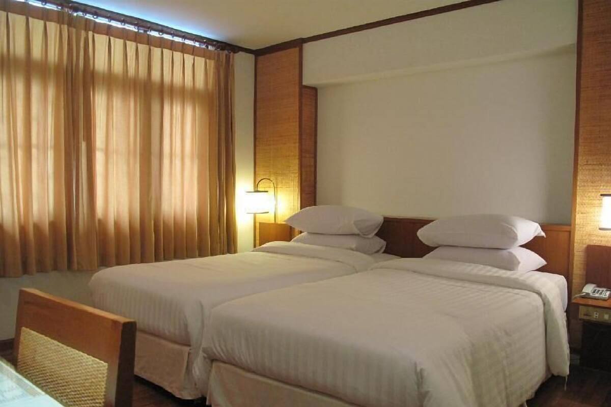 Habitación de hotel con dos camas, un escritorio, una silla, una lámpara y un teléfono.