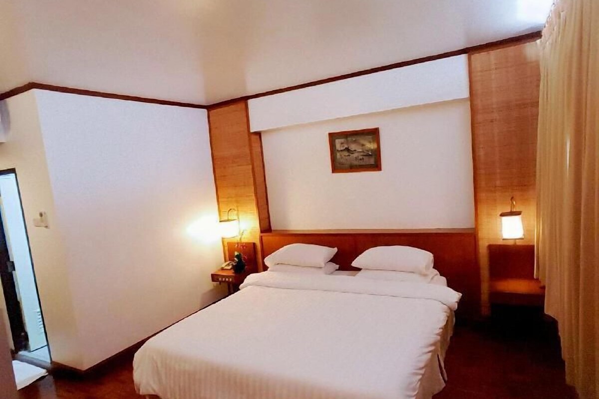 Ein Hotelzimmer mit einem großen Bett, zwei Nachttischen mit Lampen, einem Holzkopfstück und einem Bild an der Wand.