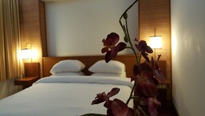 A hotel room with a bed, two bedside lamps, and a potted orchid. - Dusit Hotel at Sakon Nakhon (Sakon Nakhon)