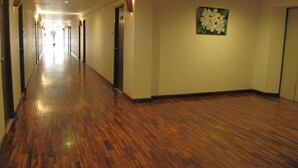 A hotel corridor with wooden flooring, doors, and wall-mounted lighting. - Dusit Hotel at Sakon Nakhon (Sakon Nakhon)